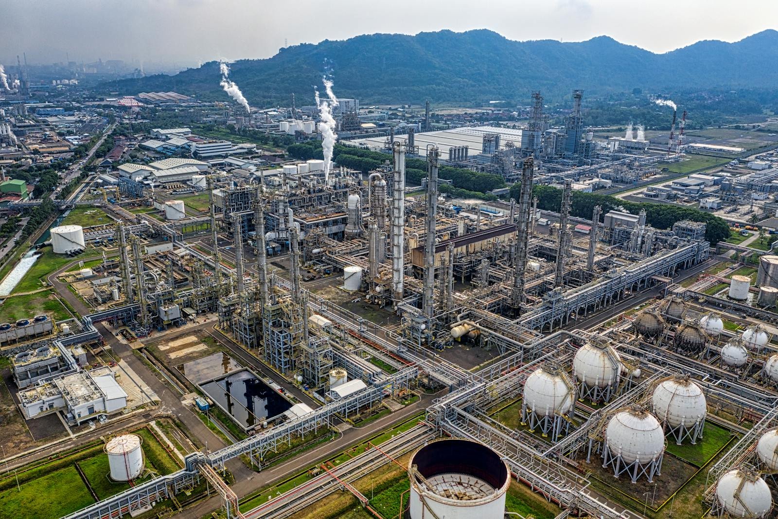 Aerial view of a tank storage terminal — refining columns and spherical pressure vessels with classified-area pipework.